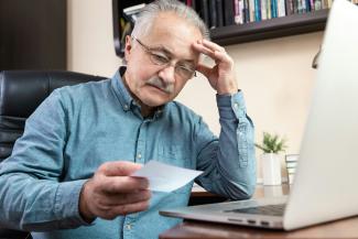 a man holding a pen and looking at a laptop by Volodymyr Hryshchenko courtesy of Unsplash.